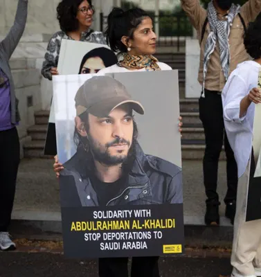 Demonstranten van Amnesty International houden een poster van Abdulrahman Al-Khalidi vast met de tekst Stop deportaties naar Saoedi-Arabië