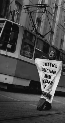 Een demonstrant loopt langs een tram in Sofia met een handgeschilderd spandoek dat gerechtigheid, bescherming en vrijheid voor Abdulrahman eist